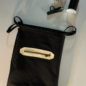 Puede incluir: Bolsa de costura negra con cord&oacute;n y bolsillo con cremallera color crema. Incluye un alfiletero negro con alfileres amarillos, hilo negro y tijeras negras peque&ntilde;as. Ideal para proyectos de costura y manualidades.