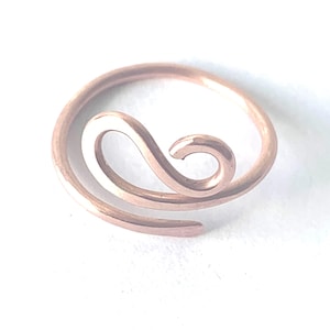 May include: A rose gold-toned metal ring featuring a continuous, open-ended design that curves into a central swirl. The band has a smooth, polished finish and a circular shape that remains open at one end, creating a fluid, wave-like aesthetic.