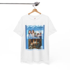 May include: White t-shirt with a blue graphic featuring the text "The Water OFFICIAL" and images of people. Below the images is the text "4 ELEMENTS ENGLOT". The shirt is hanging on a wooden hanger.