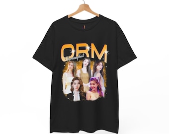 May include: Black t-shirt featuring a graphic of six women with the text "ORM Kornnaphat" in an orange and gold design. The t-shirt is hanging on a wooden hanger.