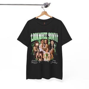May include: Black t-shirt with a retro graphic design. The text "LOOKMHEE SONYA" is in green, and there are images of several women. The names "Lookmhee Pengpapat" and "Somya Saranphat" are also printed on the shirt.