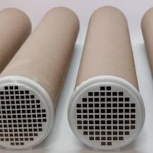 May include: Six cylindrical cardboard tubes with white plastic ends featuring a grid of small square holes. The tubes are beige and arranged horizontally, with the white ends facing the viewer.