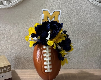 Decorazione a tema football ispirata ai Michigan Wolverines con fiori e colori giallo mais e blu.