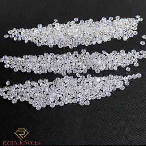 May include: A collection of small, clear, round-cut diamonds arranged in three horizontal rows against a black background. The diamonds sparkle, reflecting light. The logo "RZITA JEWELS" is at the bottom.