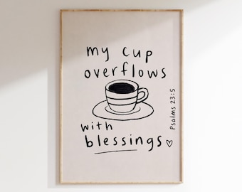 May include: A framed wall art print on a light beige background featuring a black hand-drawn illustration of a coffee cup on a saucer. The text reads: my cup overflows with blessings, and Psalms 23:5, accompanied by a small hand-drawn heart symbol.