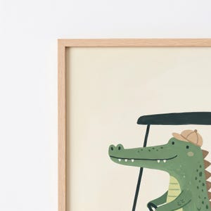 May include: A framed wall art print featuring a green crocodile wearing a tan cap while driving a dark green golf cart. The illustration is set against a solid cream-colored background and is enclosed in a light-toned wooden frame.