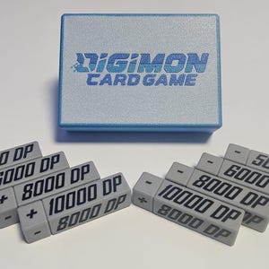 May include: A blue box with the text "DIGIMON CARD GAME" on the top.  There are ten gray rectangular blocks with black text on them.  The text on the blocks reads "5000 DP", "6000 DP", "8000 DP", and "10000 DP".  Some of the blocks have a plus sign and some have a minus sign.