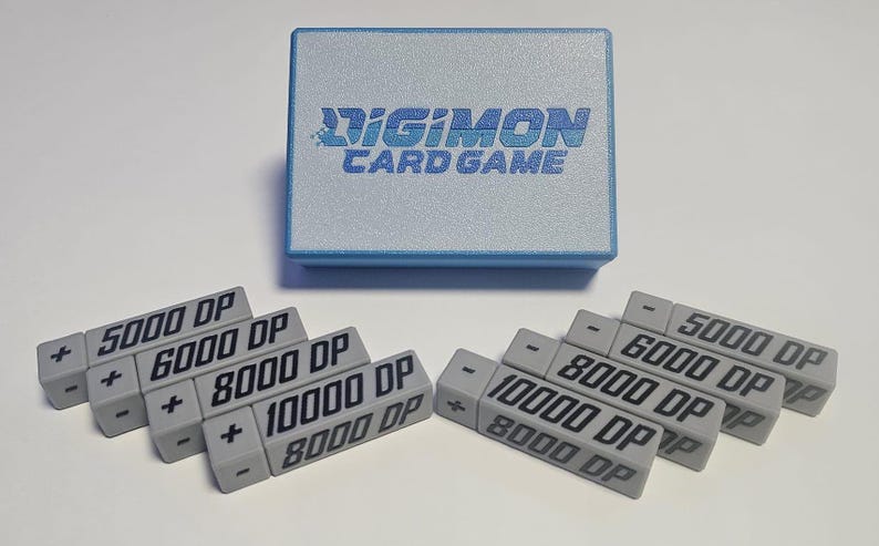 May include: A blue box with the text "DIGIMON CARD GAME" on the top.  There are ten gray rectangular blocks with black text on them.  The text on the blocks reads "5000 DP", "6000 DP", "8000 DP", and "10000 DP".  Some of the blocks have a plus sign and some have a minus sign.