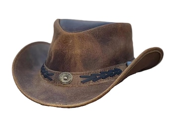 Puede incluir: Un sombrero vaquero de cuero marrón con una banda trenzada negra y un acento metálico. El sombrero tiene un aspecto desgastado y está hecho de cuero genuino.