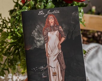 Peut inclure: Une couverture de livre avec un fond sombre représentant une femme aux cheveux roux et une robe blanche tenant une balance. Le texte "The Justice" est écrit en cursive en haut de la couverture.