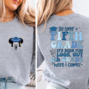May include: A light gray sweatshirt with a Mickey Mouse graduation design on the front and text on the back. The front features Mickey wearing a graduation cap with the year 2025. The back says "So long Fifth Grade" and "Look out 6th Grade".