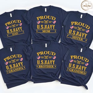 May include: Navy blue t-shirts with gold text and patriotic graphics. Each shirt says "PROUD U.S. NAVY" with a family member title: Dad, Mom, Sister, Grandpa, Brother, and Grandma. The design includes American flag hearts.
