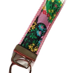 May include: A pink and black floral key chain with a silver key ring.