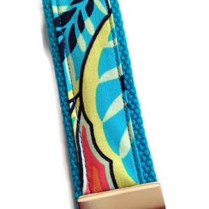 May include: A turquoise blue key chain with a colorful floral pattern and a silver key ring.