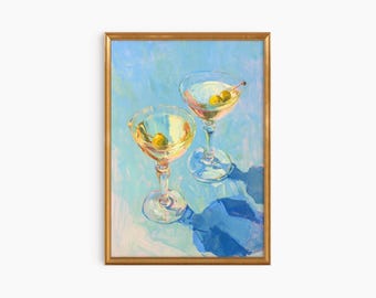 Puede incluir: Dos copas de martini con aceitunas sobre un fondo azul. Las copas están llenas de un líquido transparente y tienen un aspecto helado. El fondo es azul claro con un toque de amarillo.