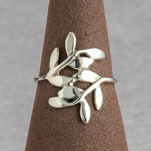 May include: A silver ring with a delicate design of intertwining branches and leaves.