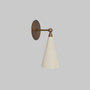 May include: A wall-mounted sconce featuring a circular bronze backplate and a conical off-white shade. The arm and connection point are bronze. The sconce has a minimalist design.