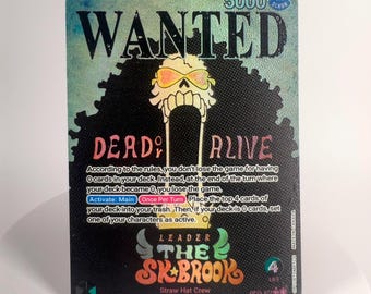 May include: A rectangular trading card featuring a Wanted poster design with a skull character wearing sunglasses. The card displays the text WANTED, DEAD OR ALIVE, and THE SK-BROOK, along with game rules, a 5000 power value, and a 4 life indicator.