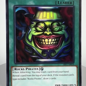 May include: A rectangular trading card titled ROCKS.D.XEBEC featuring a green, smiling pot-like character with a wide mouth and yellow teeth. The card includes the text LEADER, ROCKS PIRATES, and game instructions regarding attacking, trashing cards, and drawing.