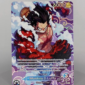 Peut inclure: Carte à collectionner avec Monkey D. Luffy de la série "One Piece". Fond violet et blanc, Luffy en action. Texte : "6000", "Strike", "Leader", "Life 3", et informations de la carte.