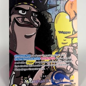 May include: A One Piece trading card featuring Marshall D. Teach, also known as Blackbeard, with a dark hat and long black hair. The card displays the text Marshall D. Teach, 5000 power, and game rules including Trigger and Leader labels.