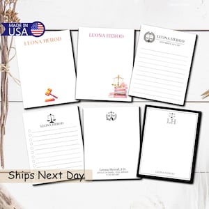May include: A collection of white notepads with various designs and text, including the name "LEONA HEROD" in different fonts and colors. Some pads feature a gavel, scales of justice, and lined pages. The phrase "MADE IN USA" is visible.