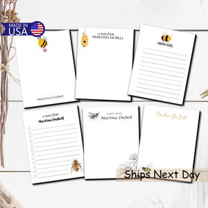 May include: White notepads with bee and floral illustrations. Each notepad features the text "a note from Martina DuBell" or "Martina DuBell". Some notepads have lined or bulleted pages. The phrase "Made in USA" is visible.