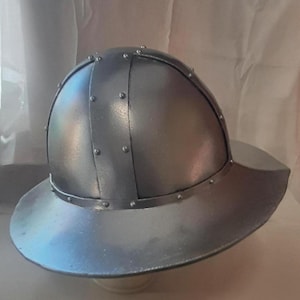 May include: A silver helmet with a wide brim and a rounded top. The helmet is decorated with small metal rivets.