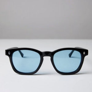 May include: Black sunglasses with blue lenses. The sunglasses have a classic, rounded shape.