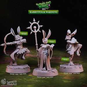Puede incluir: Tres figuras en miniatura detalladas de personajes con forma de conejo etiquetados como "Rabbitfolk Archer", "Rabbitfolk Cleric" y "Rabbitfolk Monk". Las figuras están sobre bases circulares, con alturas de 40 mm, 50 mm y 38 mm. El texto "Woodland Heroes 963 Rabbitfolk Wardens" está en la parte superior.