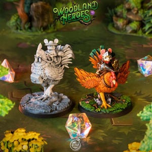 Puede incluir: Dos figuras en miniatura detalladas de criaturas del bosque. Una es una figura gris con forma de pollo con un ratón montado en su espalda. La otra es una figura gris con forma de pollo con un ratón en su espalda. Las figuras están sobre una base verde con un fondo de bosque. El texto "Woodland Heroes" está en la parte superior.
