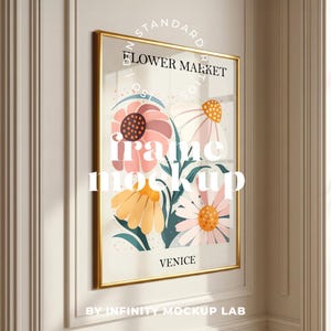May include: A framed art print with a floral design in a gold frame. The print features pink, yellow, and white flowers, with the text "FLOWER MARKET" and "VENICE". The frame is displayed on a white wall.