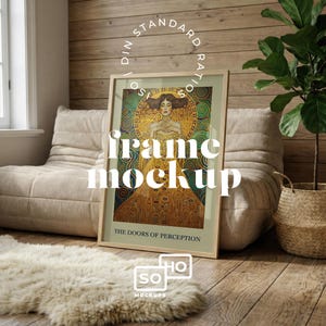 Puede incluir: Un cuadro enmarcado con una mujer con un vestido dorado y el texto "THE DOORS OF PERCEPTION". El marco es de madera clara. La imagen está en una habitación con una silla beige, una alfombra mullida y una planta en maceta.