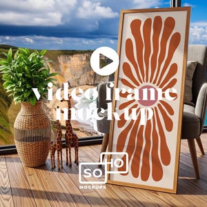 Puede incluir: Una impresión artística enmarcada con un diseño floral en tonos naranja y rosa, apoyada contra un sillón gris. La escena incluye un jarrón tejido con vegetación, jirafas de madera y una vista panorámica del océano. El texto "video frame mockup" es visible.