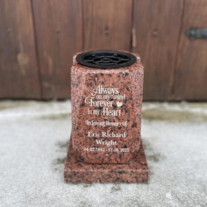 Puede incluir: Un jarrón conmemorativo de granito rojo con una rejilla floral negra en la parte superior. El jarrón está inscrito con las palabras "Always on my mind Forever in my Heart" y el nombre "Eric Richard Wright" con fechas.
