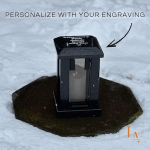 Könnte beinhalten: Schwarze Gedenklaterne mit einer transparenten Glasscheibe, auf einem dunklen Steinsockel. Die Laterne hat ein spitzes Dach und trägt den Text "PERSONALIZE WITH YOUR ENGRAVING". Die Laterne ist mit dem Text "In loving memory of Wendy Anderson Sprague 09.30.68 - 11.15.23" graviert.