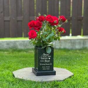 Könnte beinhalten: Eine rechteckige Grabvase aus schwarzem Granit mit der Gravur Always on my mind FOREVER in my Heart In loving Memory Of Jane Swon 1965-2025, bestückt mit einem Strauß aus tiefroten Rosen und grünen Blättern.