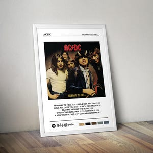 Puede incluir: Un póster blanco con una foto en blanco y negro de la banda de rock AC/DC. Los miembros de la banda están de pie frente a un fondo negro. El póster tiene el nombre de la banda y el título del álbum "Highway to Hell" impreso en texto negro. La lista de canciones del álbum está impresa debajo de la foto.