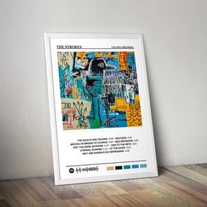May include: A framed print of The Strokes' "The New Abnormal" album art. The artwork is an abstract design in blue, yellow, and white, with song titles and a Spotify code. The white frame leans against a wooden surface.