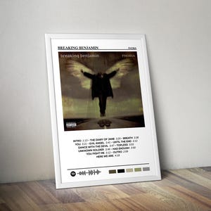 May include: A framed poster for Breaking Benjamin's "Phobia" album. The artwork shows a figure with wings. The poster includes the album title, band name, and tracklist. A Spotify code is at the bottom. The poster is in a white frame.