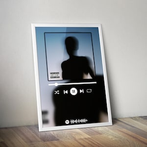 May include: White framed art print featuring a blurred silhouette of a person against a blue background. The design includes a music player interface with play, pause, and skip controls, and a Spotify code.