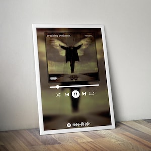 May include: Framed print of the "Phobia" album cover by Breaking Benjamin, showing a figure with wings. The print includes a Spotify-style player interface at the bottom. The text "Breaking Benjamin" and "Phobia" are visible.