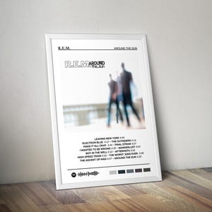 May include: A white poster with a black and white photo of three people walking away from the camera. The poster has the text "R.E.M. Around the Sun" and a list of song titles and their lengths.