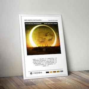 May include: A framed poster featuring the album art for "Dark Before Dawn" by Breaking Benjamin. The artwork shows a bright yellow circle against a dark background. The band's name and album title are displayed in white text.
