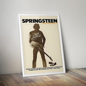 May include: A vintage concert poster for Bruce Springsteen's "Born to Run" album. The poster features a black and white photo of Springsteen holding a guitar, with the text "SPRINGSTEEN" in bold black letters at the top. The poster also includes the text "THE BOTTOM LINE-AUG-13-17" and "BORN TO RUN: THE NEW ALBUM FROM BRUCE SPRINGSTEEN. COMING SOON ON COLUMBIA RECORDS AND TAPES."