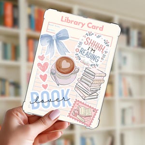 Op de afbeelding: Een doorzichtige tablethoes met een bibliotheekkaartontwerp. Het heeft een lichtblauwe strik, hartjes, een koffiekopje en de tekst "Shhh, I'm reading". De woorden "book lover" staan ook op de hoes. De achtergrond is een vage boekenkast.