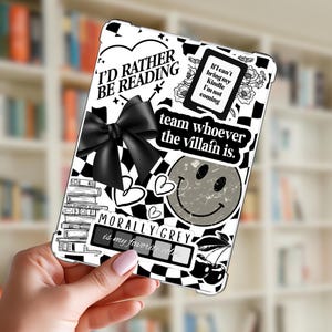 May include: A black and white tablet case with a checkerboard pattern and various graphics. The case features text that reads "I'd rather be reading," "team whoever the villain is," and "morally grey is my favorite color." A black bow and a smiley face are also visible.