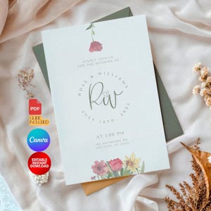 Puede incluir: Una invitación de boda con un diseño floral. La invitación es para Rose & Williams y la fecha es el 13 de julio de 2025. La invitación está impresa en un fondo blanco con un borde azul claro.