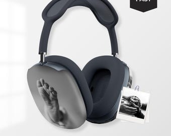 May include: Dark gray headphones with a black and white image of a baby's foot on the ear cup. The text "PERSONALIZED PROTECTION IN STYLE" is at the bottom. The headphones have a slim profile case and are scratch resistant.