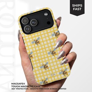 May include: A phone case featuring a yellow and white gingham check pattern with a repeating bee motif. The case has a black camera cutout area and the letters TS printed near the bottom. It is labelled as a MagSafe tough magnetic case.
